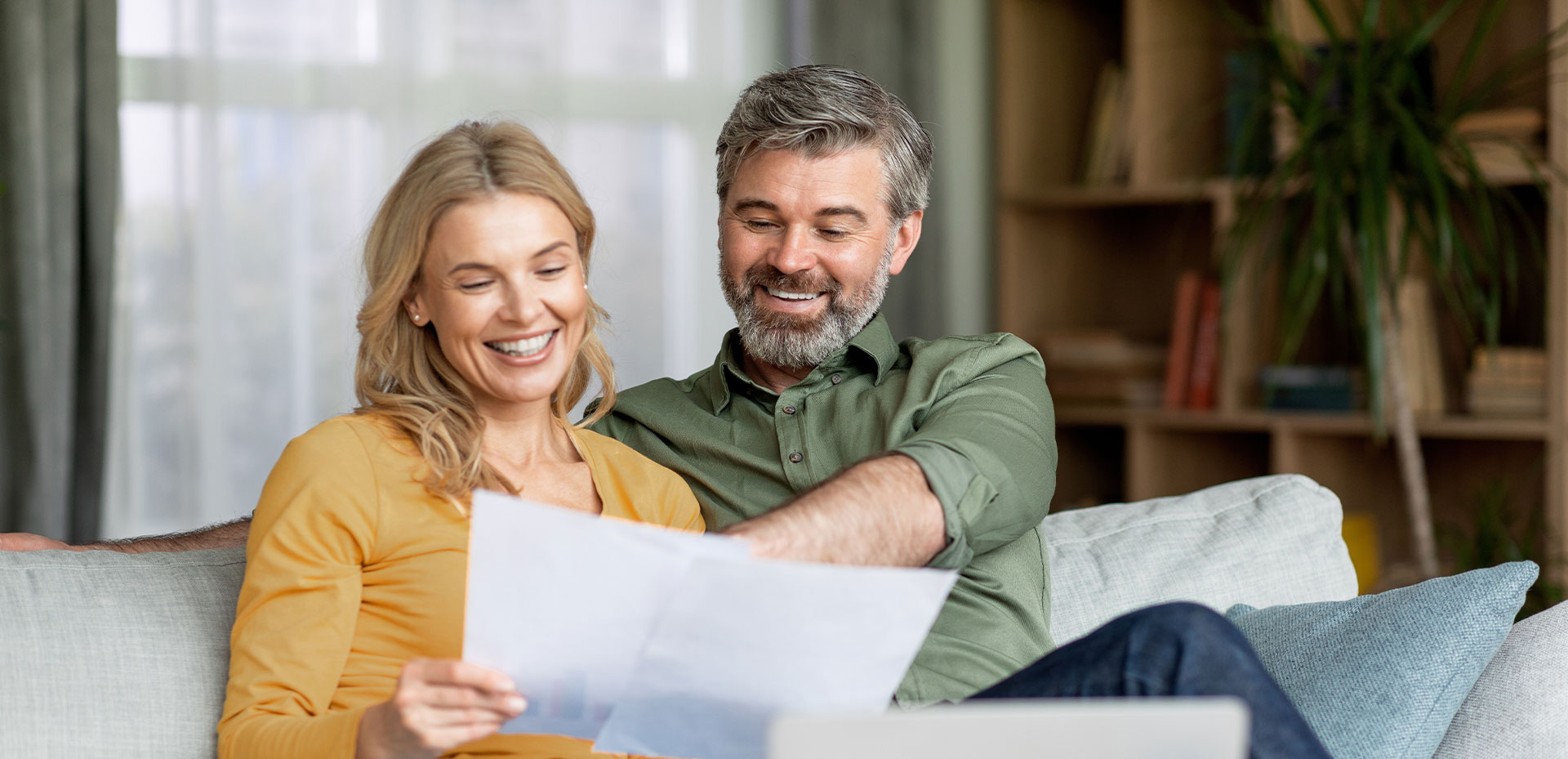 Middle-aged couple smiles while reviewing documents.