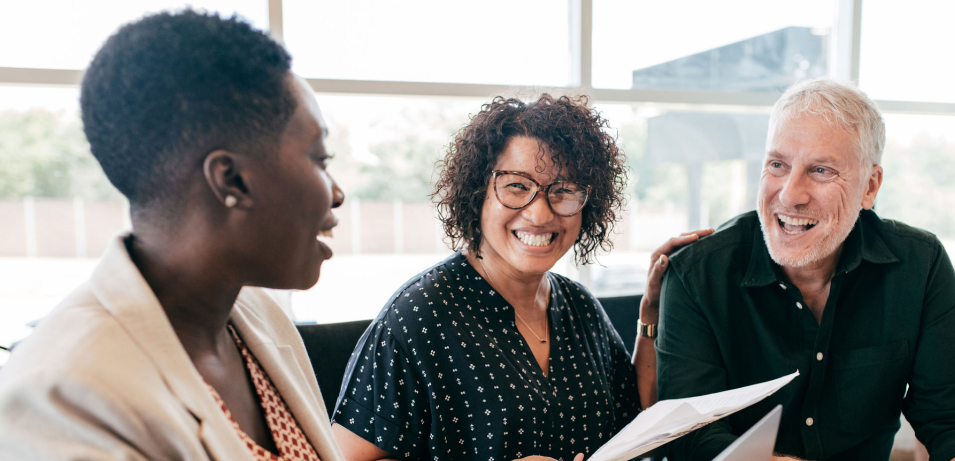 Professionals smile during conversation in an office building.