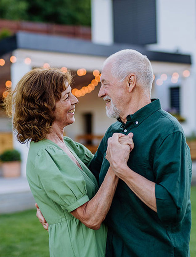 Aged couple dances, smiling and looking into each other's eyes.