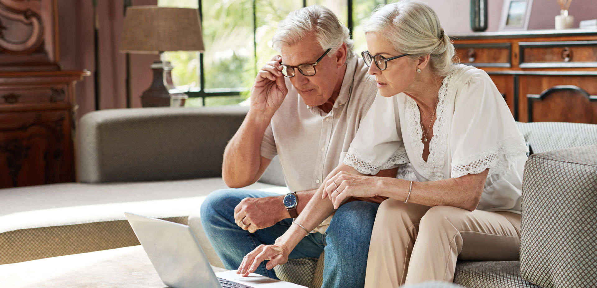 Aged couple looks at laptop together.